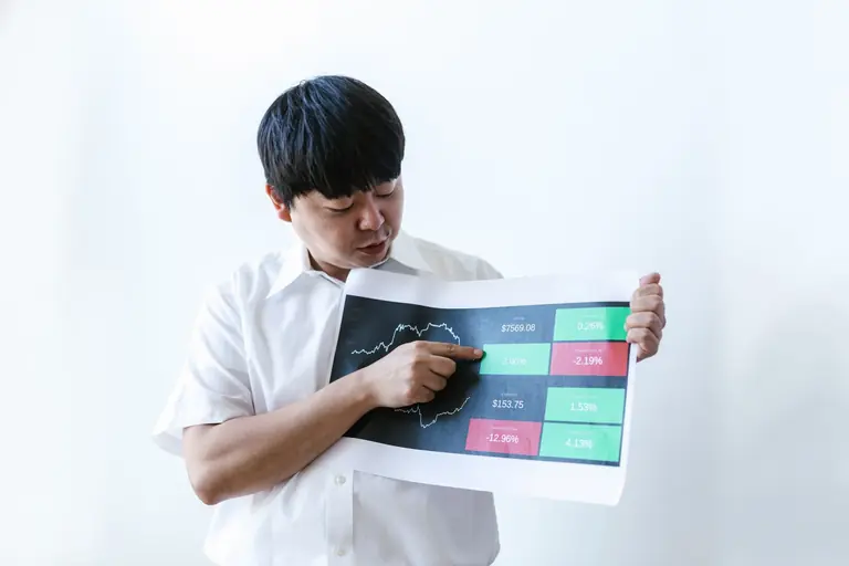 Asian businessman in white shirt presenting cryptocurrency market data on chart.